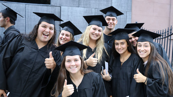 Students at investiture smiling and giving the thumbs up sign.