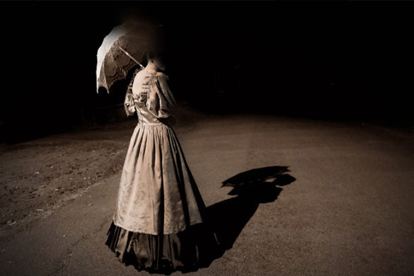 Ghostly woman holding umbrella on an ominous street.