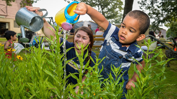 Child watering the garden of the Sister's of St. Joseph with SJC Long Island child study major Mallory McClafferty.