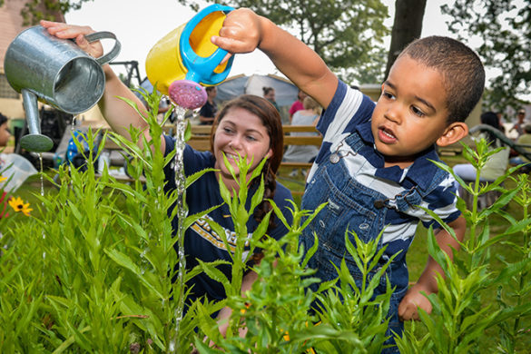 Child watering the garden of the Sister's of St. Joseph with SJC Long Island child study major Mallory McClafferty.