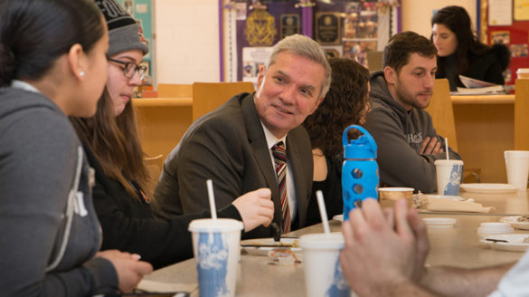 Students and administrator talking at table.