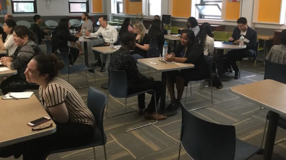 Adults and students seated across from each other.