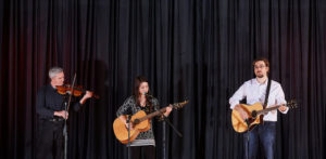 Adults playing musical instruments on stage.