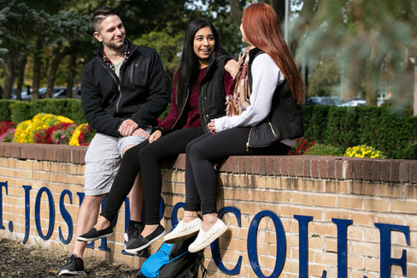 SJC Long Island students sitting on St. Joseph's College sign.