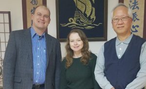 Three adults standing and grinning.