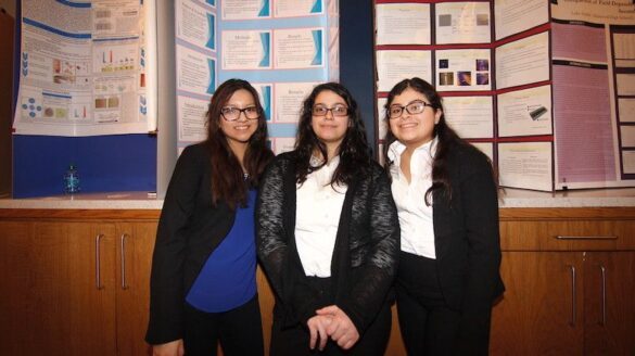 Three students at past event, standing.