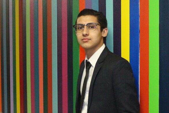 Student standing in front of colorful wall.