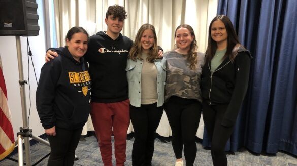 Students standing with a professor.