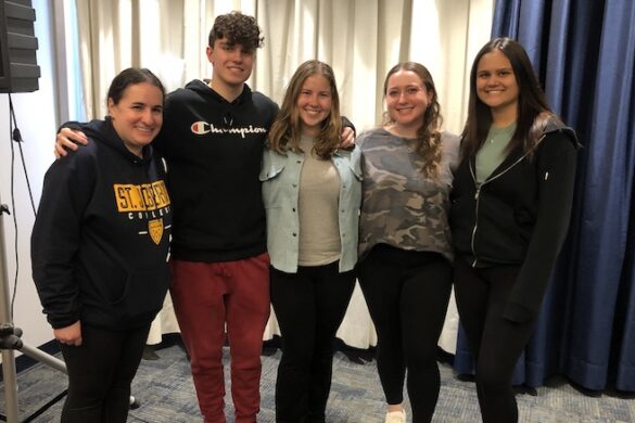 Students standing with a professor.